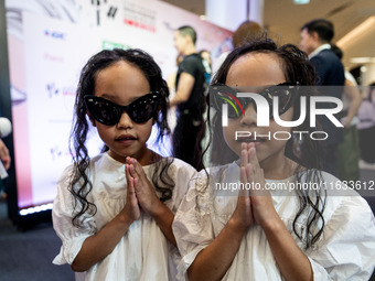 Young twin models give a 'Wai' greeting on the red carpet after walking on the runway during Day 2 of Bangkok International Fashion Week at...