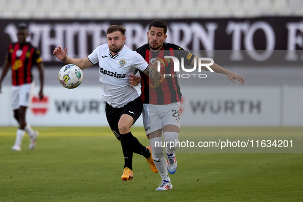 In Ta' Qali, Malta, on October 2, 2024, Jurgen Degabriele of Hibernians is closely challenged by Juan Carlos Corbalan of Hamrun Spartans dur...