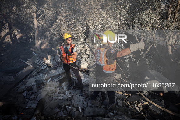 Palestinian Civil Defense rescuers attempt to extinguish fires following an Israeli airstrike in Deir al-Balah, central Gaza Strip, on Octob...