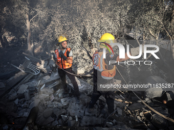 Palestinian Civil Defense rescuers attempt to extinguish fires following an Israeli airstrike in Deir al-Balah, central Gaza Strip, on Octob...