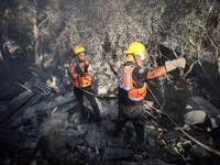 Palestinian Civil Defense rescuers attempt to extinguish fires following an Israeli airstrike in Deir al-Balah, central Gaza Strip, on Octob...