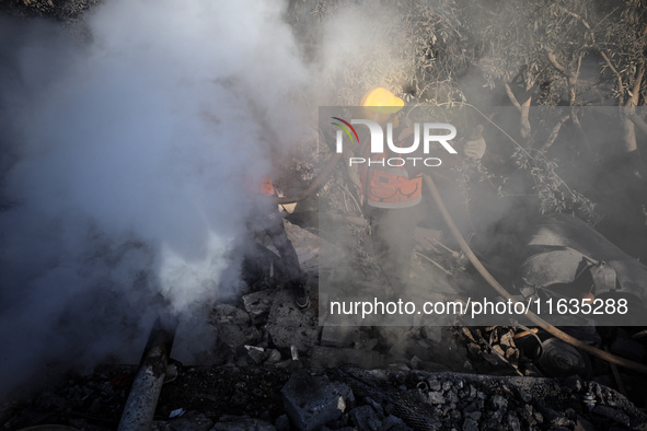 Palestinian Civil Defense rescuers attempt to extinguish fires following an Israeli airstrike in Deir al-Balah, central Gaza Strip, on Octob...