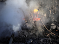 Palestinian Civil Defense rescuers attempt to extinguish fires following an Israeli airstrike in Deir al-Balah, central Gaza Strip, on Octob...