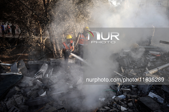 Palestinian Civil Defense rescuers attempt to extinguish fires following an Israeli airstrike in Deir al-Balah, central Gaza Strip, on Octob...