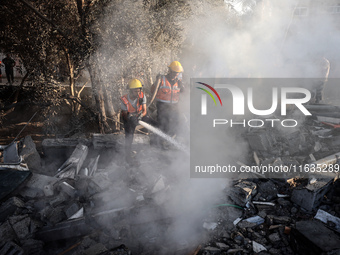 Palestinian Civil Defense rescuers attempt to extinguish fires following an Israeli airstrike in Deir al-Balah, central Gaza Strip, on Octob...