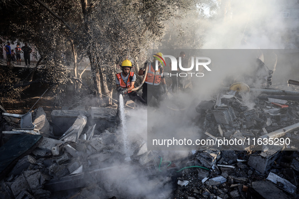 Palestinian Civil Defense rescuers attempt to extinguish fires following an Israeli airstrike in Deir al-Balah, central Gaza Strip, on Octob...