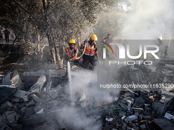 Palestinian Civil Defense rescuers attempt to extinguish fires following an Israeli airstrike in Deir al-Balah, central Gaza Strip, on Octob...