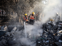 Palestinian Civil Defense rescuers attempt to extinguish fires following an Israeli airstrike in Deir al-Balah, central Gaza Strip, on Octob...