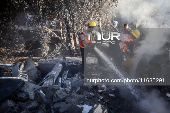 Palestinian Civil Defense rescuers attempt to extinguish fires following an Israeli airstrike in Deir al-Balah, central Gaza Strip, on Octob...