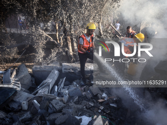 Palestinian Civil Defense rescuers attempt to extinguish fires following an Israeli airstrike in Deir al-Balah, central Gaza Strip, on Octob...