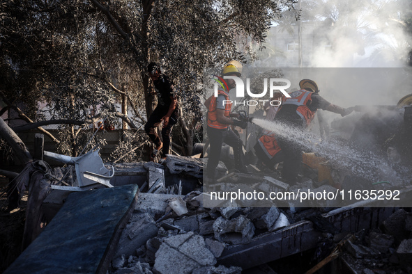 Palestinian Civil Defense rescuers attempt to extinguish fires following an Israeli airstrike in Deir al-Balah, central Gaza Strip, on Octob...