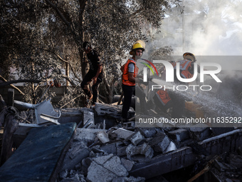 Palestinian Civil Defense rescuers attempt to extinguish fires following an Israeli airstrike in Deir al-Balah, central Gaza Strip, on Octob...