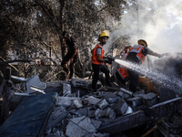 Palestinian Civil Defense rescuers attempt to extinguish fires following an Israeli airstrike in Deir al-Balah, central Gaza Strip, on Octob...