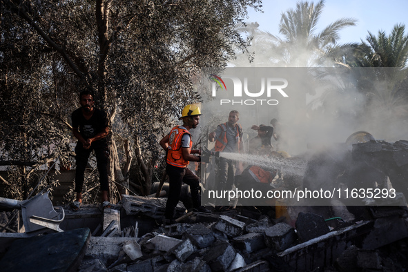 Palestinian Civil Defense rescuers attempt to extinguish fires following an Israeli airstrike in Deir al-Balah, central Gaza Strip, on Octob...