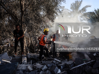 Palestinian Civil Defense rescuers attempt to extinguish fires following an Israeli airstrike in Deir al-Balah, central Gaza Strip, on Octob...