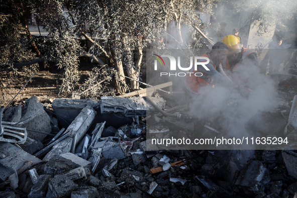 Palestinian Civil Defense rescuers attempt to extinguish fires following an Israeli airstrike in Deir al-Balah, central Gaza Strip, on Octob...