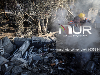 Palestinian Civil Defense rescuers attempt to extinguish fires following an Israeli airstrike in Deir al-Balah, central Gaza Strip, on Octob...