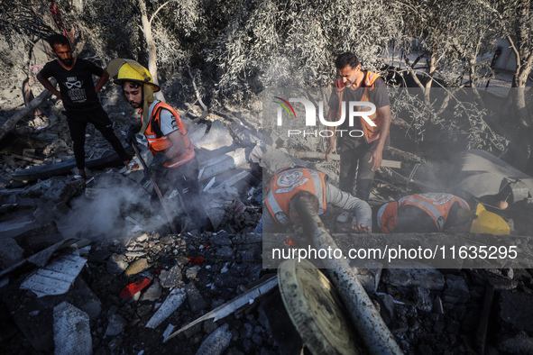 Palestinian Civil Defense rescuers attempt to extinguish fires following an Israeli airstrike in Deir al-Balah, central Gaza Strip, on Octob...