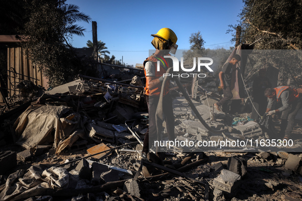 Palestinian Civil Defense rescuers attempt to extinguish fires following an Israeli airstrike in Deir al-Balah, central Gaza Strip, on Octob...