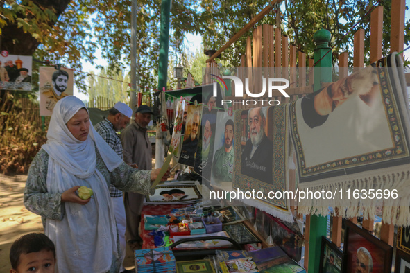 A Kashmiri Shia Muslim woman purchases a placard of Hezbollah leader Sayyed Hassan Nasrallah during a protest against Israel following the k...