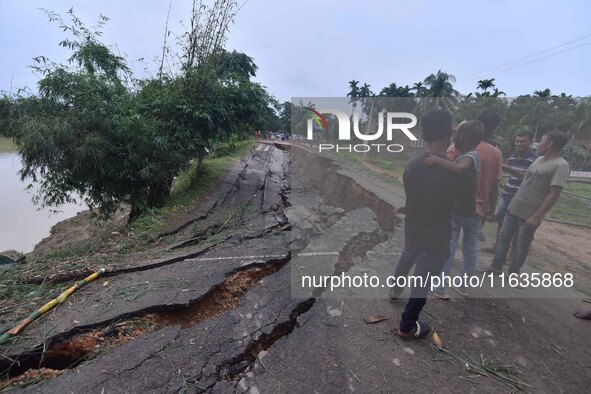 People stand near the erosion caused by the Kopilli River on a section of the PWD road near Bagalajan, which connects Raha to Kampur, in Nag...