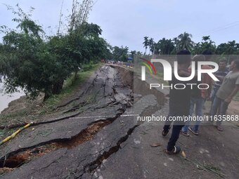 People stand near the erosion caused by the Kopilli River on a section of the PWD road near Bagalajan, which connects Raha to Kampur, in Nag...