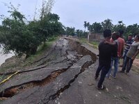 People stand near the erosion caused by the Kopilli River on a section of the PWD road near Bagalajan, which connects Raha to Kampur, in Nag...