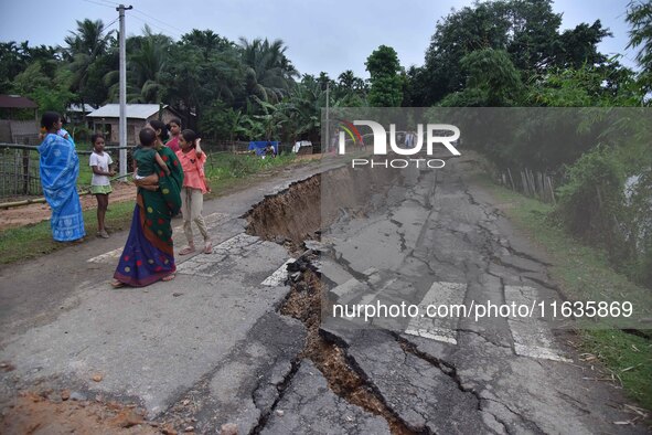 People stand near the erosion caused by the Kopilli River on a section of the PWD road near Bagalajan, which connects Raha to Kampur, in Nag...