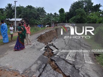 People stand near the erosion caused by the Kopilli River on a section of the PWD road near Bagalajan, which connects Raha to Kampur, in Nag...