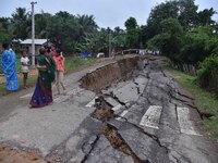 People stand near the erosion caused by the Kopilli River on a section of the PWD road near Bagalajan, which connects Raha to Kampur, in Nag...