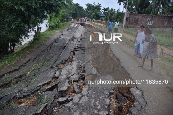 People stand near the erosion caused by the Kopilli River on a section of the PWD road near Bagalajan, which connects Raha to Kampur, in Nag...