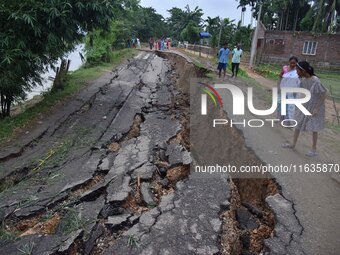 People stand near the erosion caused by the Kopilli River on a section of the PWD road near Bagalajan, which connects Raha to Kampur, in Nag...