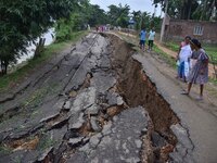 People stand near the erosion caused by the Kopilli River on a section of the PWD road near Bagalajan, which connects Raha to Kampur, in Nag...