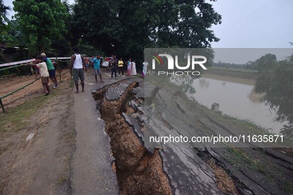 People stand near the erosion caused by the Kopilli River on a section of the PWD road near Bagalajan, which connects Raha to Kampur, in Nag...