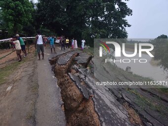 People stand near the erosion caused by the Kopilli River on a section of the PWD road near Bagalajan, which connects Raha to Kampur, in Nag...