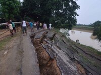 People stand near the erosion caused by the Kopilli River on a section of the PWD road near Bagalajan, which connects Raha to Kampur, in Nag...