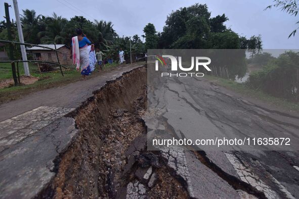 People stand near the erosion caused by the Kopilli River on a section of the PWD road near Bagalajan, which connects Raha to Kampur, in Nag...