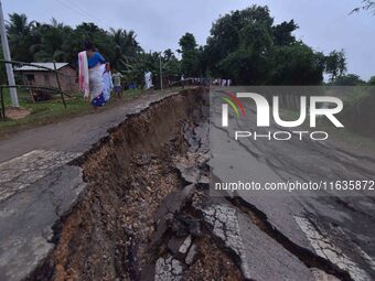 People stand near the erosion caused by the Kopilli River on a section of the PWD road near Bagalajan, which connects Raha to Kampur, in Nag...