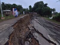 People stand near the erosion caused by the Kopilli River on a section of the PWD road near Bagalajan, which connects Raha to Kampur, in Nag...