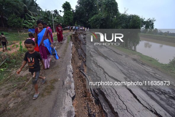 People stand near the erosion caused by the Kopilli River on a section of the PWD road near Bagalajan, which connects Raha to Kampur, in Nag...