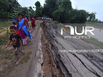 People stand near the erosion caused by the Kopilli River on a section of the PWD road near Bagalajan, which connects Raha to Kampur, in Nag...