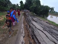 People stand near the erosion caused by the Kopilli River on a section of the PWD road near Bagalajan, which connects Raha to Kampur, in Nag...