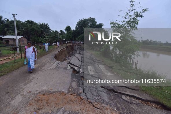 People stand near the erosion caused by the Kopilli River on a section of the PWD road near Bagalajan, which connects Raha to Kampur, in Nag...