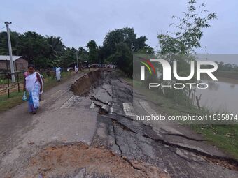 People stand near the erosion caused by the Kopilli River on a section of the PWD road near Bagalajan, which connects Raha to Kampur, in Nag...