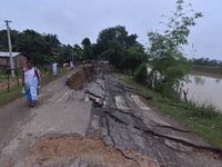 People stand near the erosion caused by the Kopilli River on a section of the PWD road near Bagalajan, which connects Raha to Kampur, in Nag...