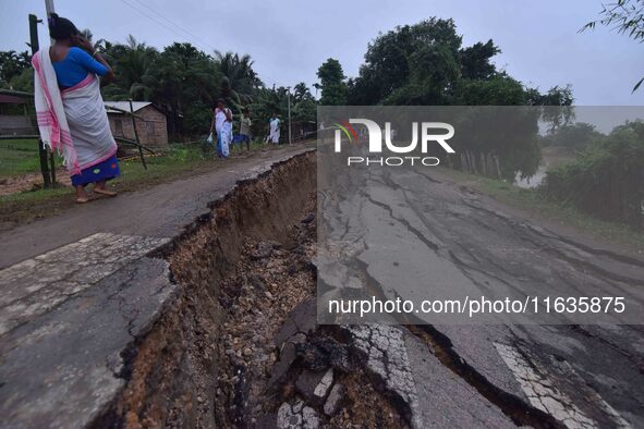 People stand near the erosion caused by the Kopilli River on a section of the PWD road near Bagalajan, which connects Raha to Kampur, in Nag...