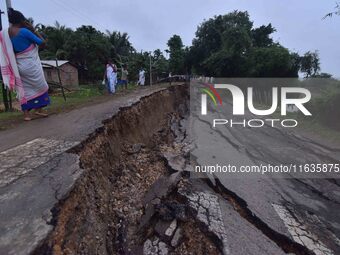 People stand near the erosion caused by the Kopilli River on a section of the PWD road near Bagalajan, which connects Raha to Kampur, in Nag...