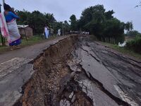 People stand near the erosion caused by the Kopilli River on a section of the PWD road near Bagalajan, which connects Raha to Kampur, in Nag...