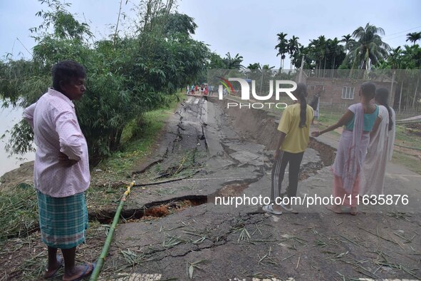 People stand near the erosion caused by the Kopilli River on a section of the PWD road near Bagalajan, which connects Raha to Kampur, in Nag...