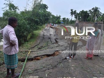 People stand near the erosion caused by the Kopilli River on a section of the PWD road near Bagalajan, which connects Raha to Kampur, in Nag...